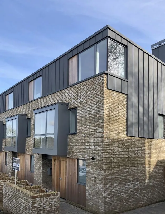 Townhouses and apartments in brick and dark standing-seam cladding, central Winchester