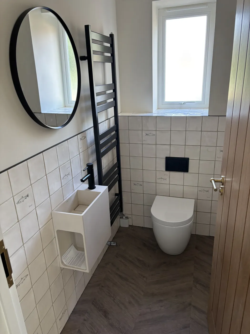 Cloakroom with white tiling, a wall-hung WC and a round mirror