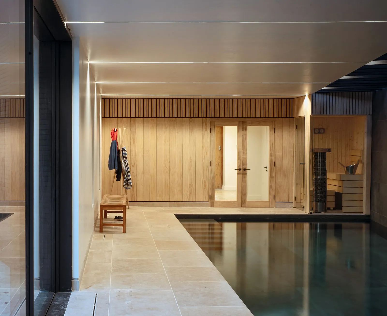 Indoor pool hall lined in oak, with stone flooring and a dark pool edge