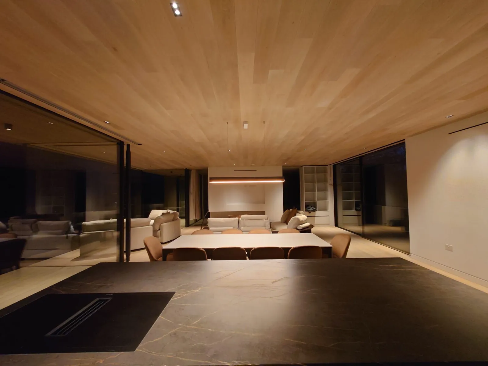 Living and dining space with a timber-lined ceiling and glazing on two sides
