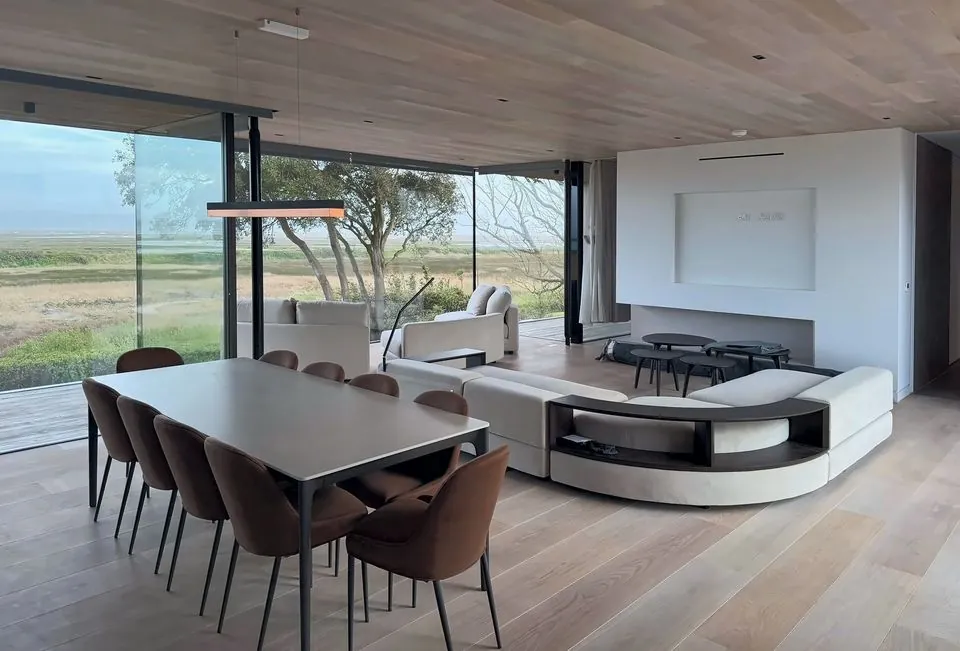 Open-plan living and dining space with a timber-lined ceiling and glazing out to the marshes