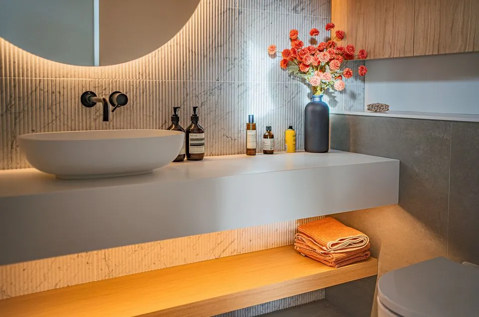 Bathroom with a floating stone vanity, vessel basin and backlit round mirror