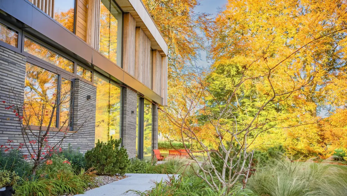 Brick and timber elevation of the Winchester house behind an autumn acer and planting