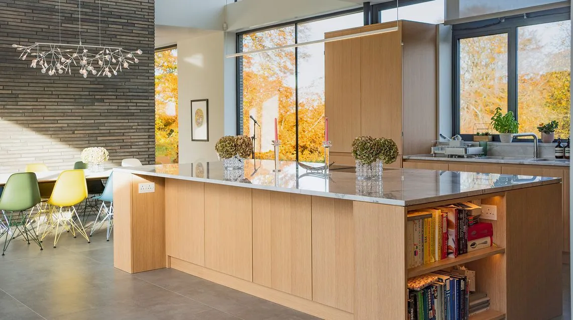 Kitchen with an oak island and built-in shelving, with glazing to the garden beyond