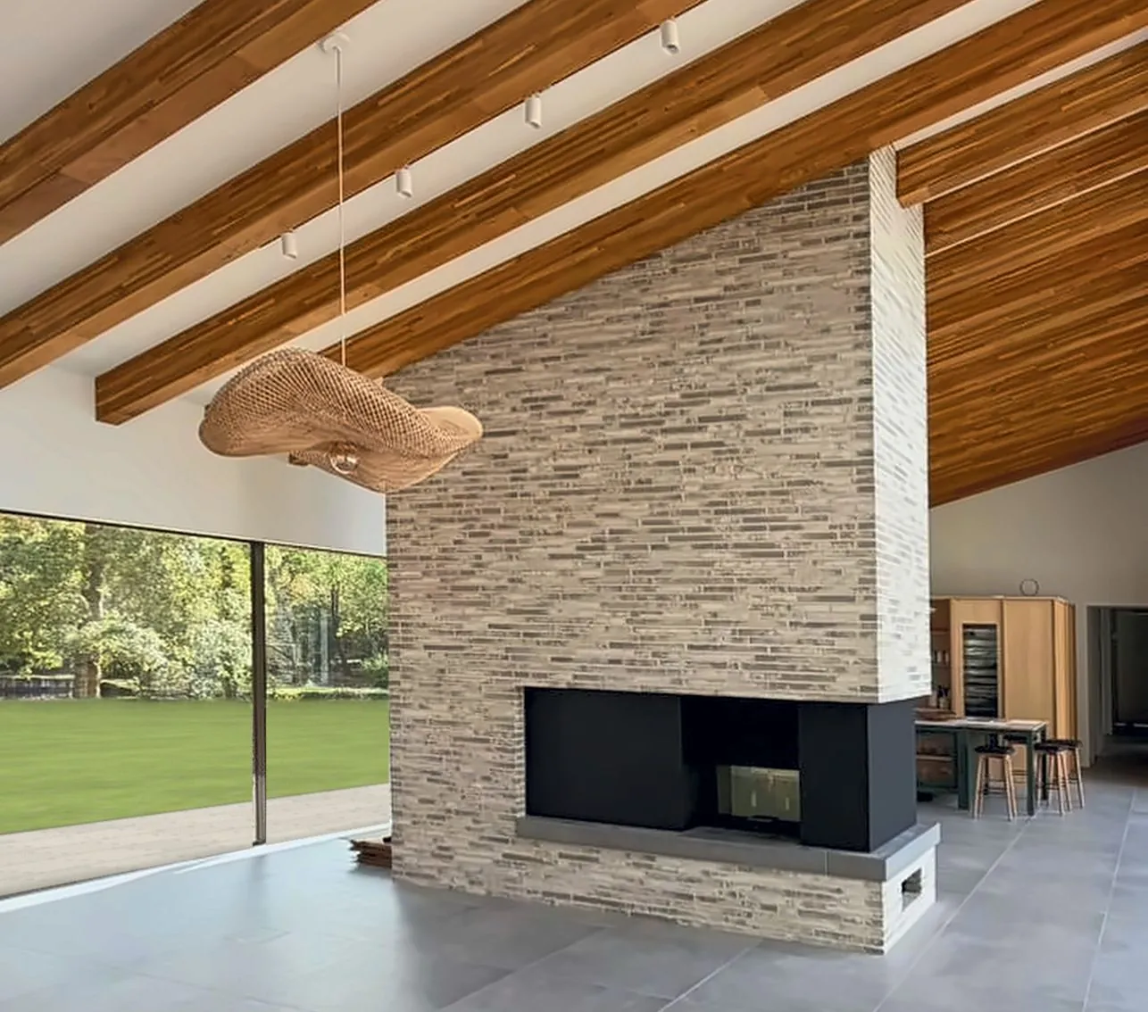 The same living space as built, with the slim-brick fireplace, timber rafters and full-height glazing