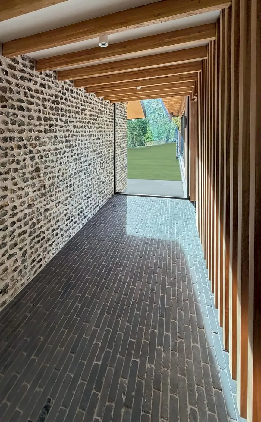 Timber colonnade running along a flint wall, with exposed rafters overhead